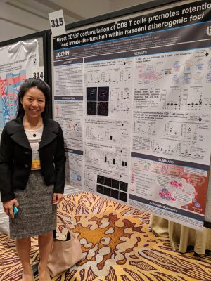 Maria Xu standing in professional attire next to her poster